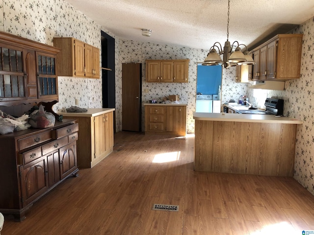 kitchen with a textured ceiling, washing machine and dryer, decorative light fixtures, and hardwood / wood-style flooring