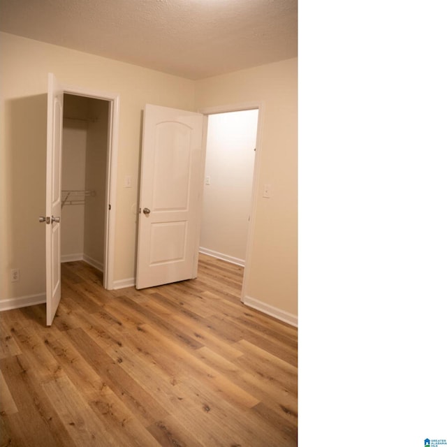 unfurnished bedroom with a closet, light hardwood / wood-style floors, and a textured ceiling