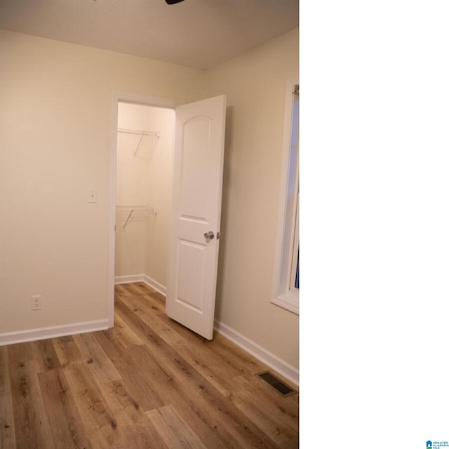 unfurnished bedroom featuring a spacious closet, light wood-type flooring, and a closet