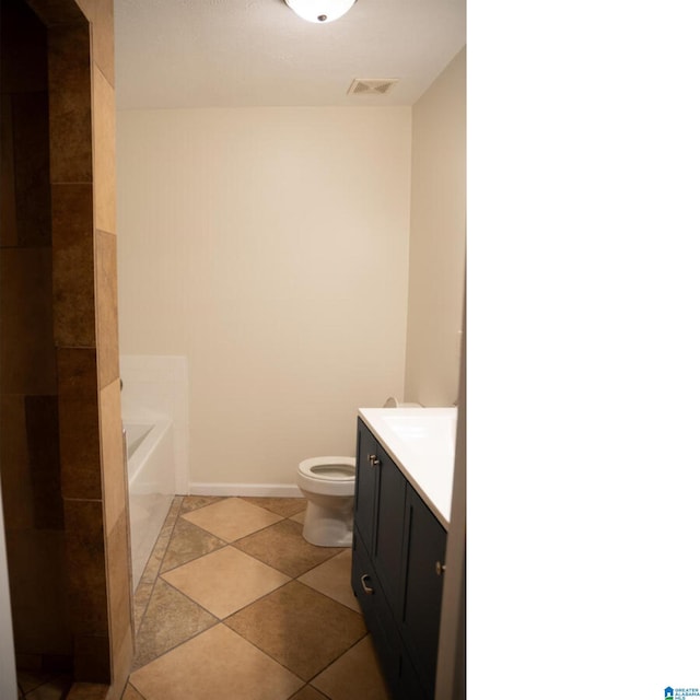 bathroom featuring tile patterned floors, a tub, vanity, and toilet