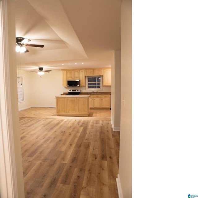 kitchen with ceiling fan, sink, white range oven, light brown cabinetry, and light wood-type flooring