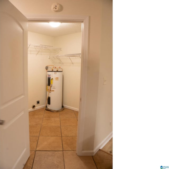 laundry room with electric dryer hookup, electric water heater, and light tile patterned floors