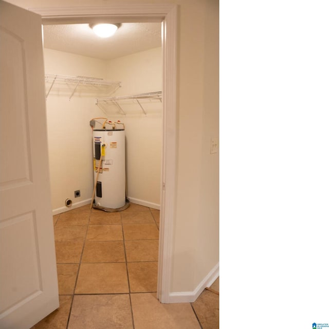 laundry room featuring electric water heater, light tile patterned floors, and hookup for an electric dryer