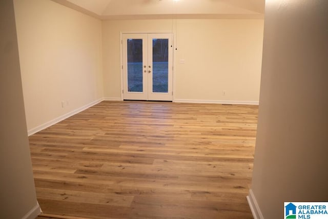 unfurnished room featuring french doors, light hardwood / wood-style floors, and vaulted ceiling