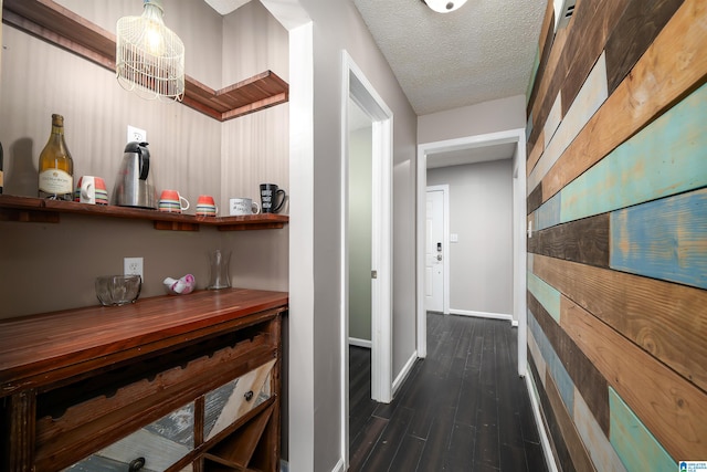 corridor with a textured ceiling, dark hardwood / wood-style floors, and an inviting chandelier