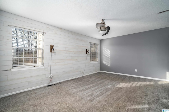 unfurnished room featuring a textured ceiling, carpet floors, and wooden walls