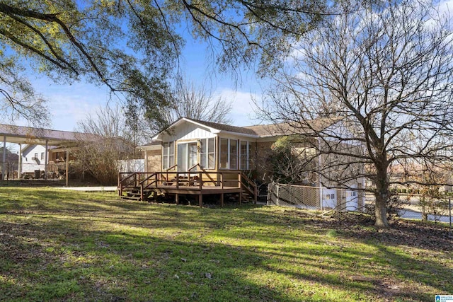 back of house featuring a lawn, a wooden deck, and a sunroom