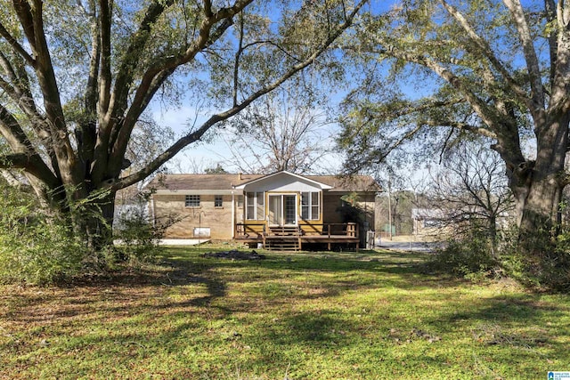 rear view of property featuring a lawn and a wooden deck