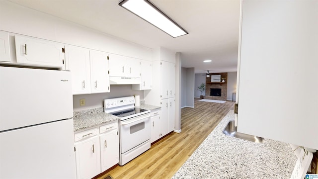 kitchen featuring light wood-type flooring, white appliances, ceiling fan, a fireplace, and white cabinetry