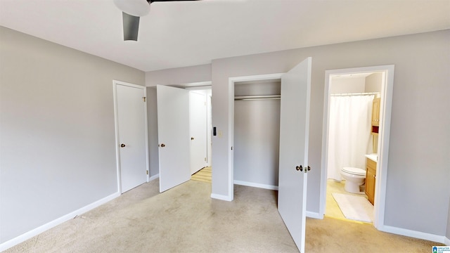 unfurnished bedroom featuring light carpet, ensuite bathroom, and ceiling fan