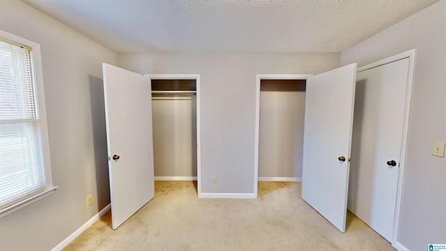 unfurnished bedroom with light colored carpet and a textured ceiling