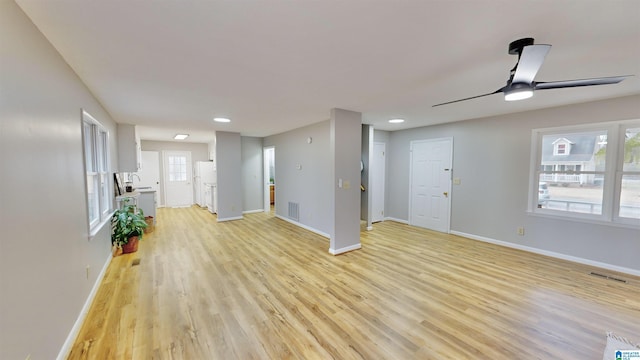 unfurnished living room featuring ceiling fan, a healthy amount of sunlight, sink, and light hardwood / wood-style flooring