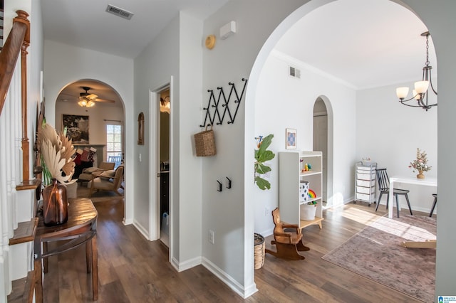 hallway featuring dark hardwood / wood-style flooring, ornamental molding, and an inviting chandelier