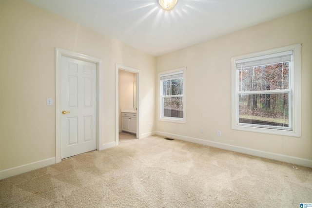 unfurnished bedroom with ensuite bath and light carpet