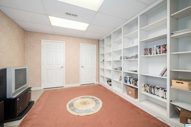 interior space with built in shelves, light carpet, and a drop ceiling