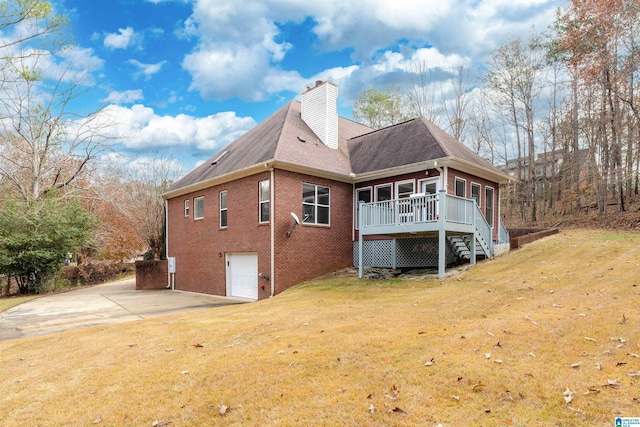 rear view of property with a lawn, a garage, and a wooden deck