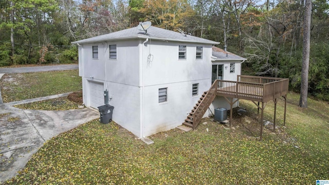 view of side of home featuring central air condition unit, a lawn, a deck, and a garage