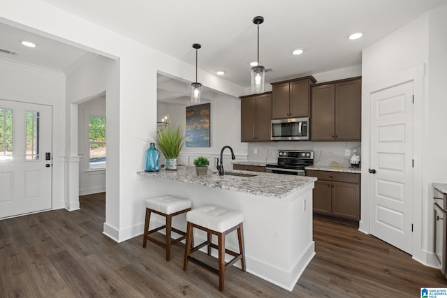 kitchen with kitchen peninsula, light stone counters, dark hardwood / wood-style flooring, and stainless steel appliances