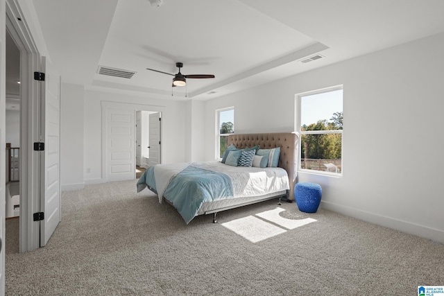 bedroom with carpet flooring, ceiling fan, and a raised ceiling