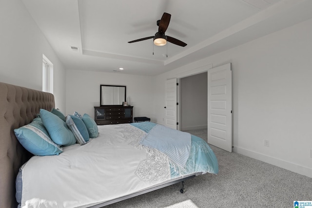 bedroom with carpet, ceiling fan, and a raised ceiling