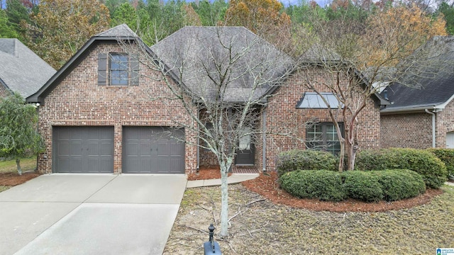 view of front of home with a garage, driveway, brick siding, and a shingled roof