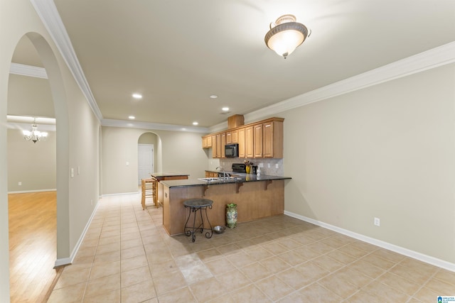 kitchen featuring kitchen peninsula, crown molding, a breakfast bar area, and sink