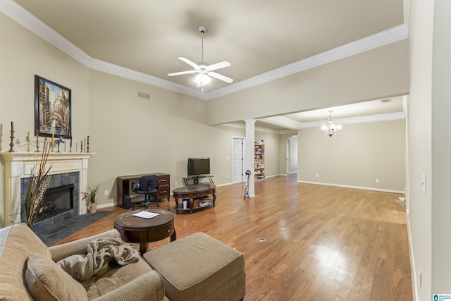 living room featuring crown molding, a fireplace, ceiling fan with notable chandelier, and hardwood / wood-style flooring