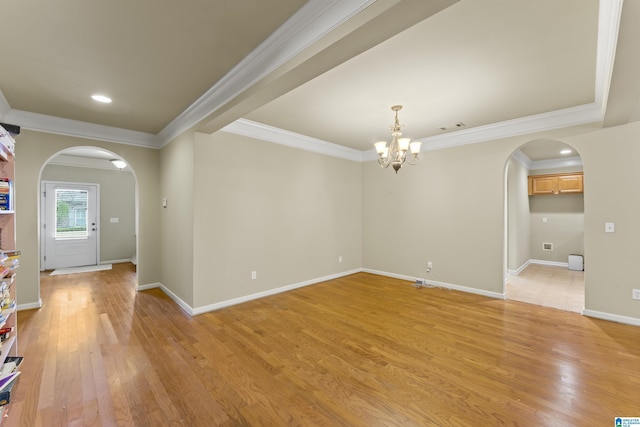 empty room featuring light wood-type flooring, crown molding, and a chandelier