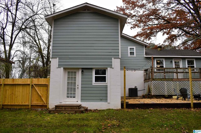 back of property with cooling unit, a deck, and a yard