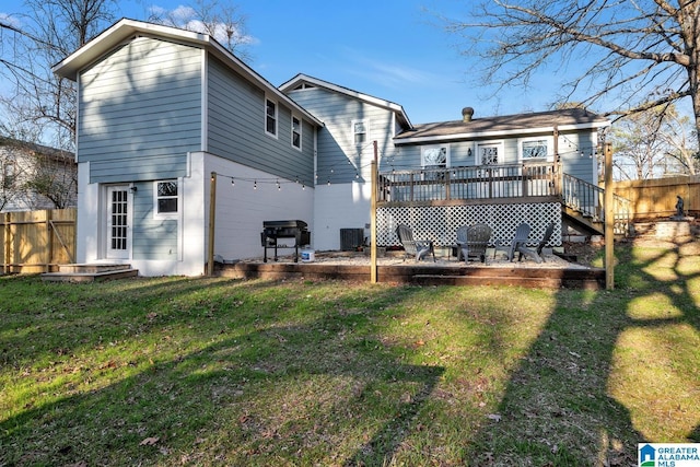 rear view of house featuring a wooden deck and a yard