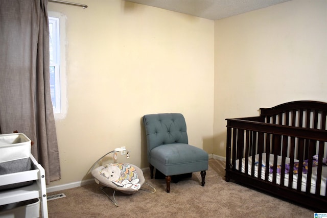 bedroom with multiple windows, light colored carpet, and a crib