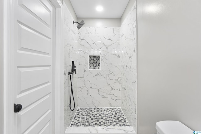 bathroom with toilet and a tile shower