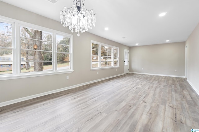 unfurnished room with an inviting chandelier and light hardwood / wood-style flooring