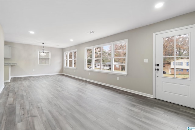 unfurnished living room with light hardwood / wood-style floors and an inviting chandelier