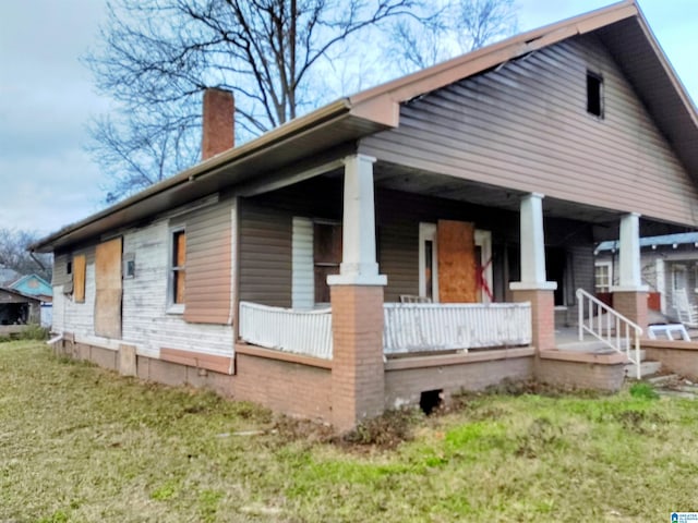 view of home's exterior with covered porch and a lawn