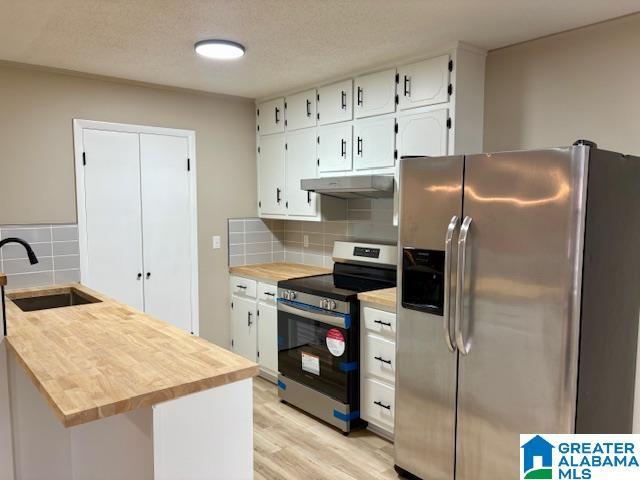 kitchen with a textured ceiling, stainless steel appliances, sink, light hardwood / wood-style flooring, and white cabinetry