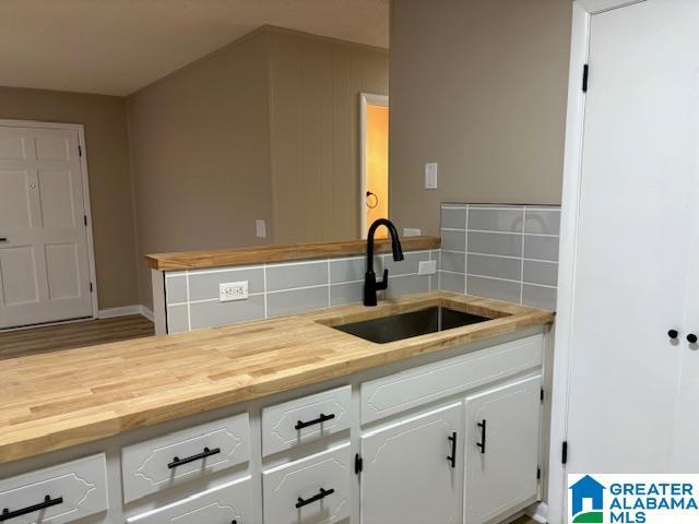 kitchen with decorative backsplash, white cabinetry, and sink