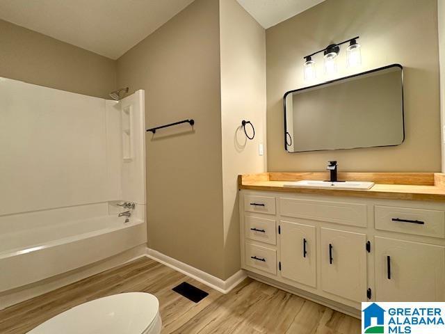 full bathroom with vanity, toilet, shower / bathing tub combination, and hardwood / wood-style flooring