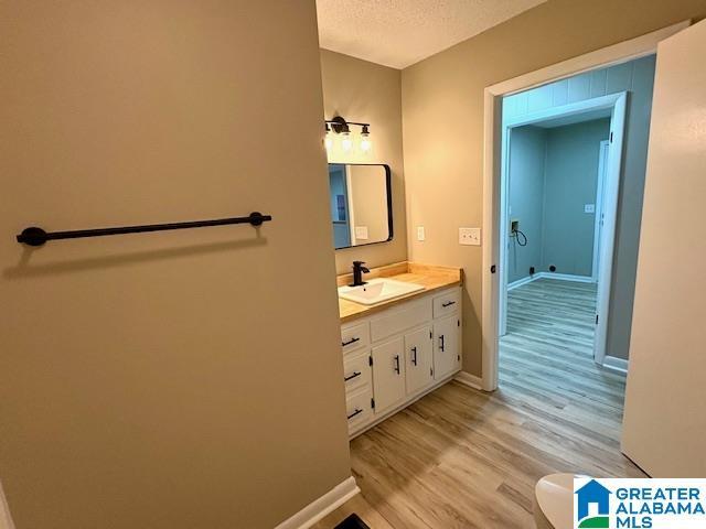 bathroom with vanity, a textured ceiling, hardwood / wood-style flooring, and toilet