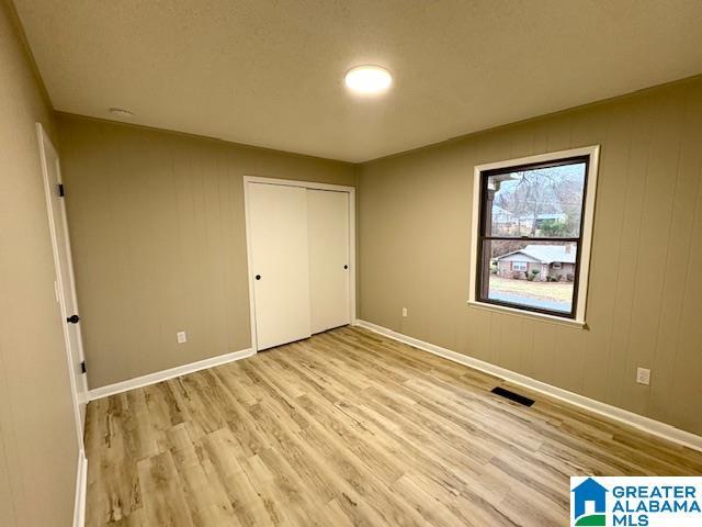 unfurnished bedroom featuring wood walls, a closet, and light wood-type flooring