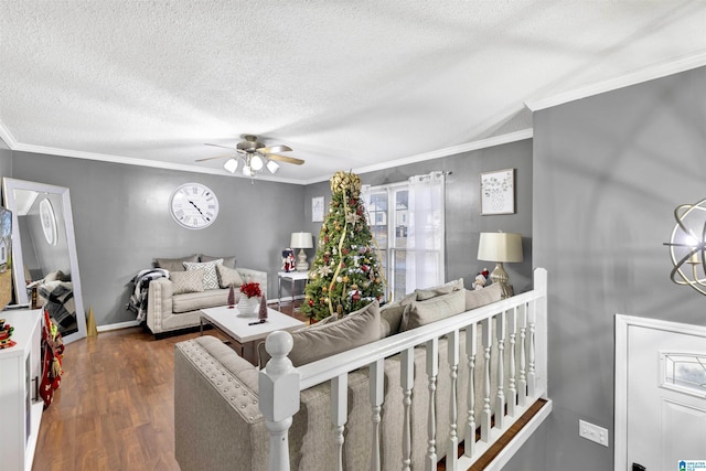 living room featuring a textured ceiling, ceiling fan with notable chandelier, dark wood-type flooring, and ornamental molding