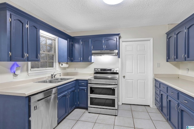 kitchen with sink, light tile patterned floors, a textured ceiling, appliances with stainless steel finishes, and blue cabinetry