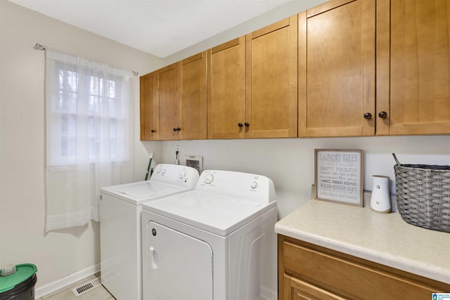 laundry room featuring cabinets, a wealth of natural light, washer and dryer, and light tile patterned flooring