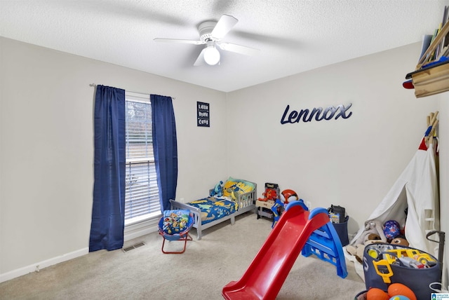 carpeted bedroom featuring ceiling fan and a textured ceiling