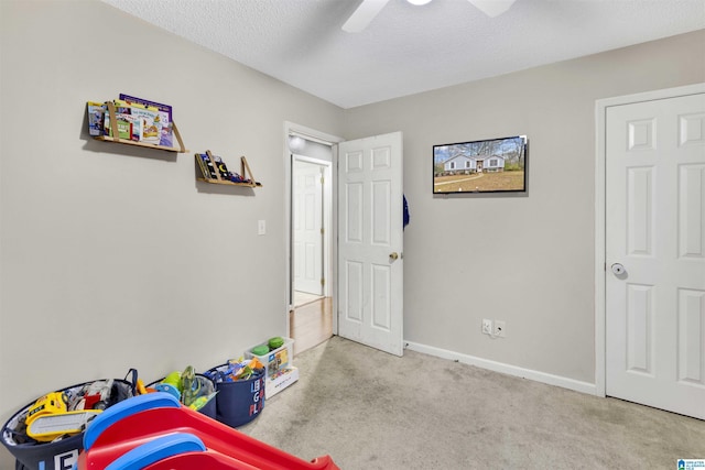 playroom featuring ceiling fan, light carpet, and a textured ceiling