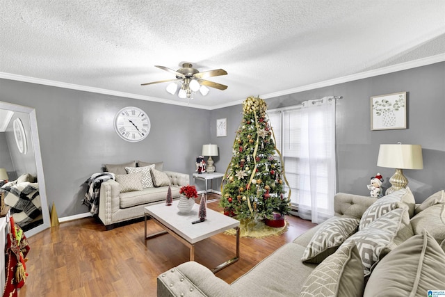 living room featuring wood-type flooring, a textured ceiling, ceiling fan, and crown molding