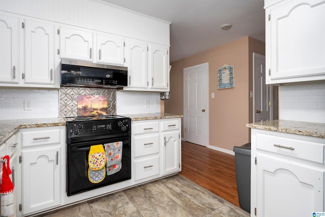 kitchen with decorative backsplash, light stone countertops, light hardwood / wood-style flooring, black range, and white cabinets