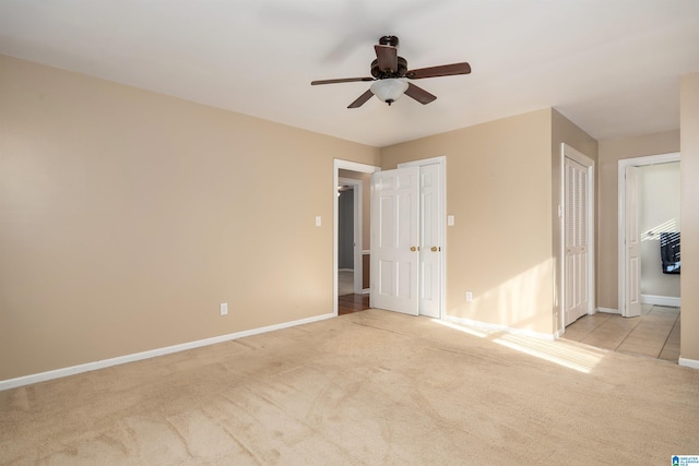 unfurnished bedroom featuring multiple closets, ceiling fan, and light colored carpet