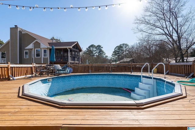 view of swimming pool with a sunroom and a deck