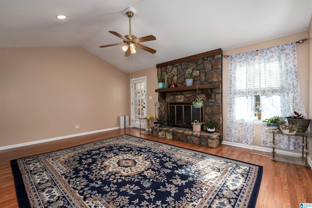 living room with hardwood / wood-style floors, ceiling fan, a fireplace, and vaulted ceiling